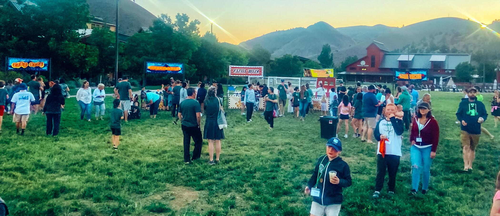 A crowd of people in a grass field at flok Family Camp West in 2023.